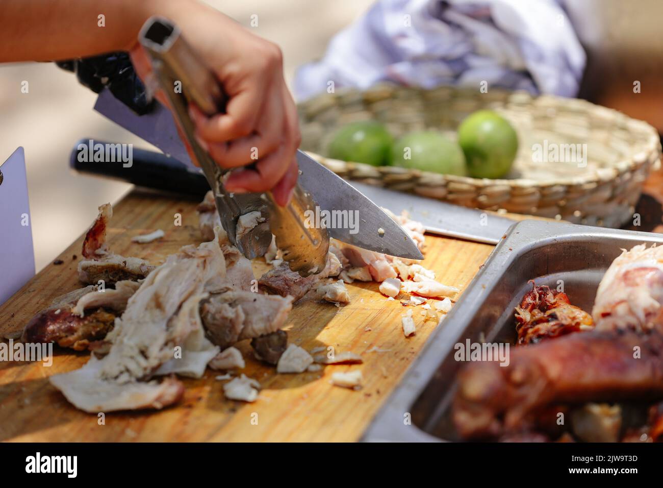 Nahaufnahme eines Küchenchefs, der das gegrillte Spanferkel schneidet Stockfoto