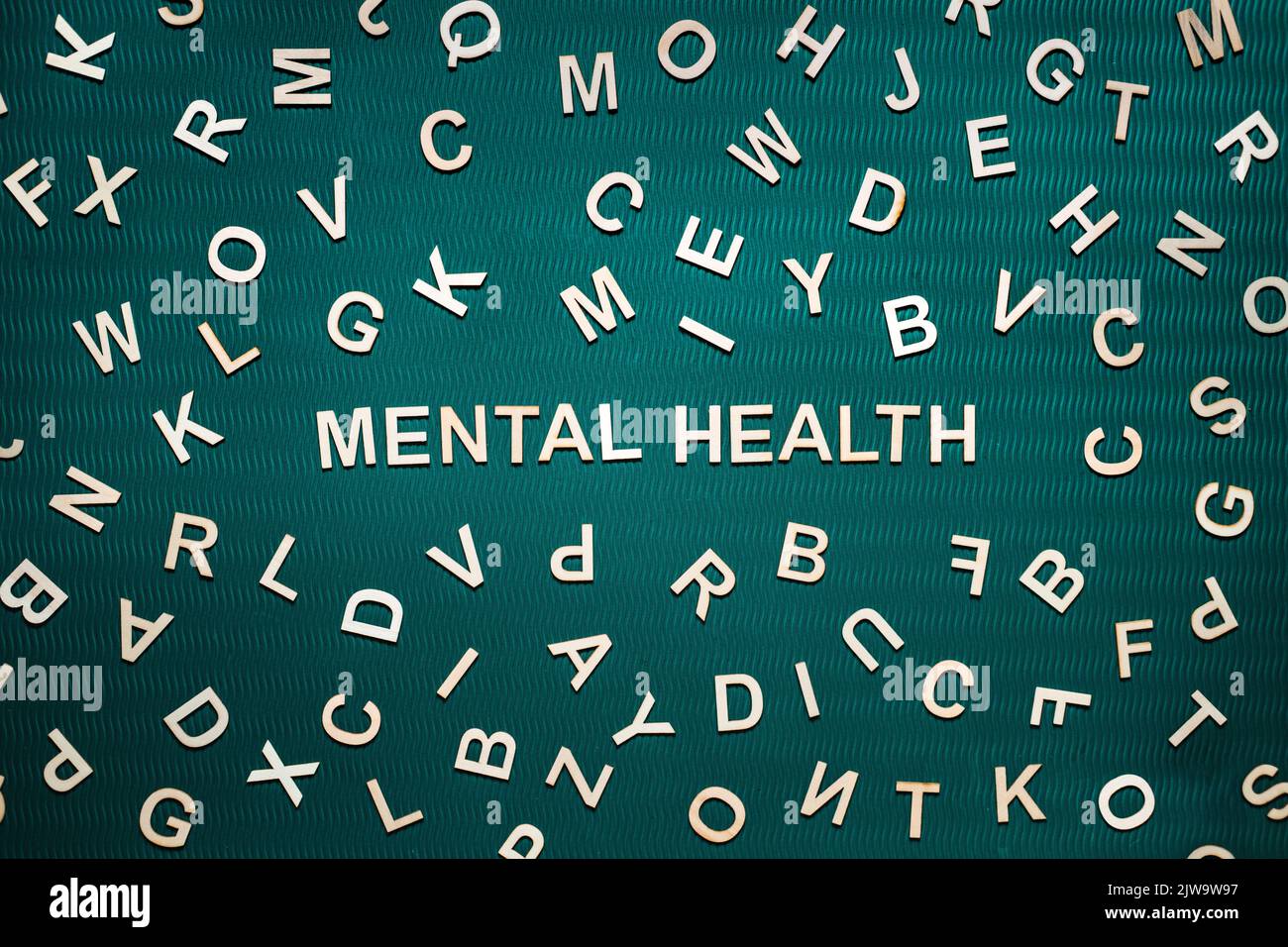 Psychische Gesundheit Wort aus Holzbuchstaben. Text für psychische Gesundheit auf grünem Hintergrund mit vielen anderen Buchstaben. Stockfoto