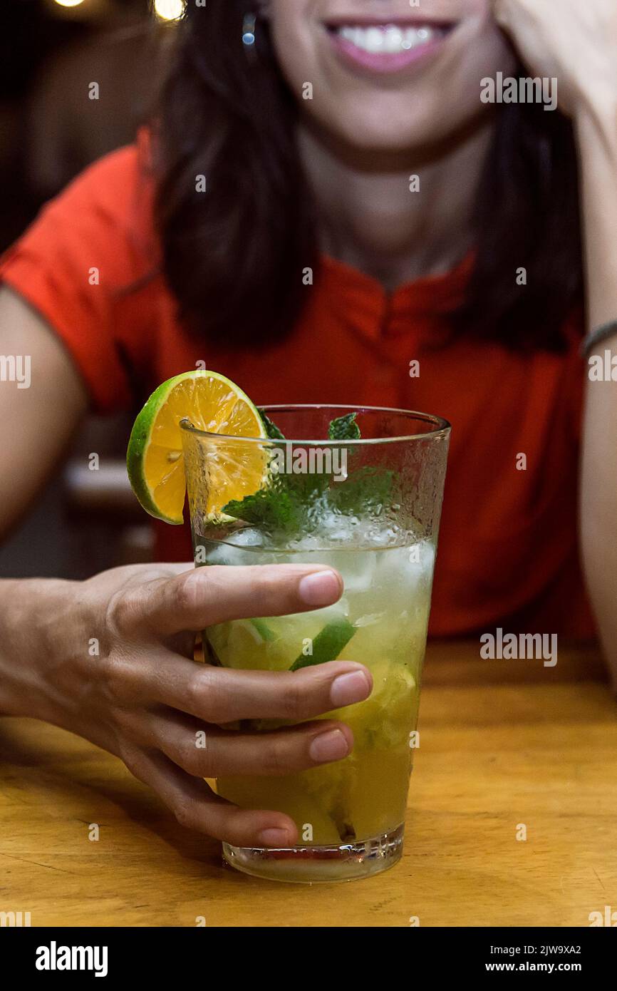 Frau an der Bar mit einem Cocktail in der Hand, während sie einen Abend voller Spaß genießt. Nachtleben Stockfoto