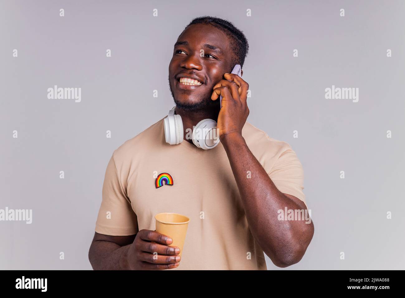 latino-Mann im lässigen grauen T-Shirt mit kabellosen Kopfhörern und Smartphone Stockfoto