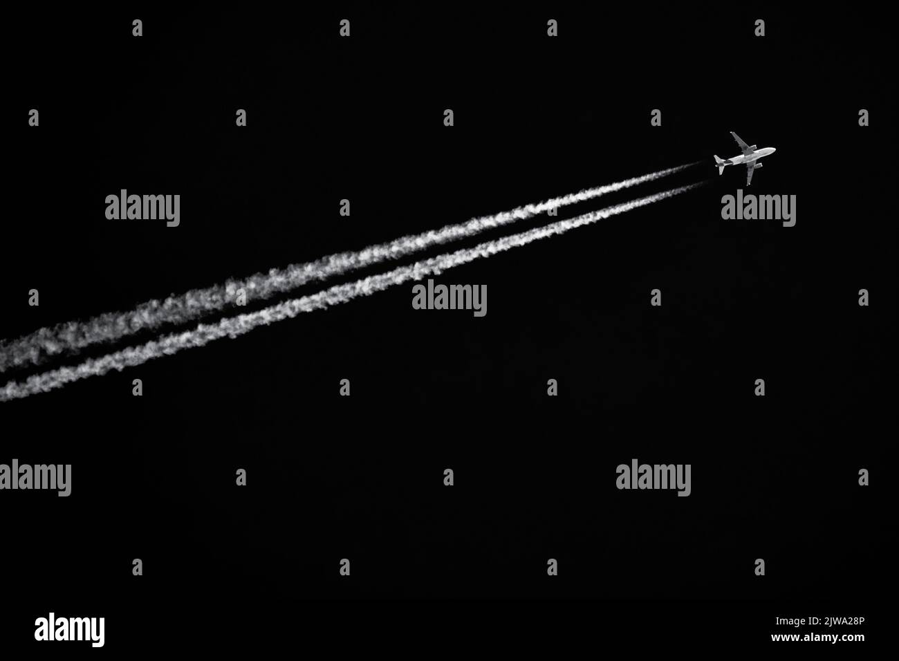Zweimotoriger Jetliner mit Kondensstreifen, die in schwarzem Himmel fliegen Stockfoto