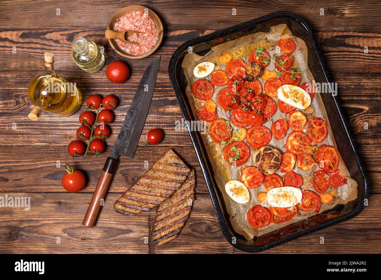 Gebackene Tomaten mit Olivenöl und Kräutern in einer Auflaufform. Gesunde Ernährung. Sommeressen auf dem Grill. Stockfoto