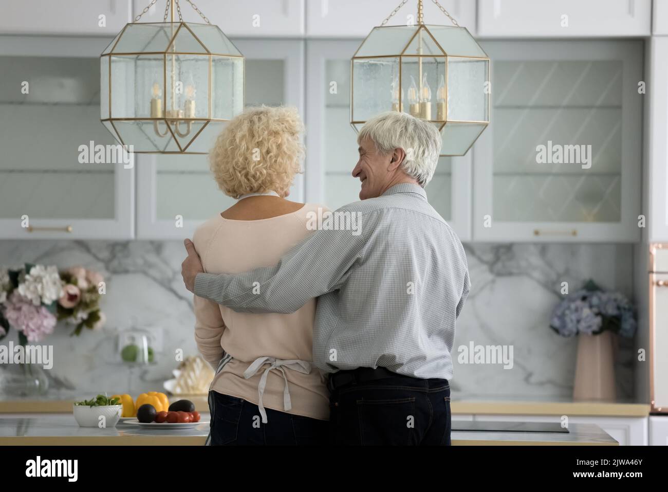 Glückliches reifes Paar, das gemeinsam kocht und am Tisch steht Stockfoto