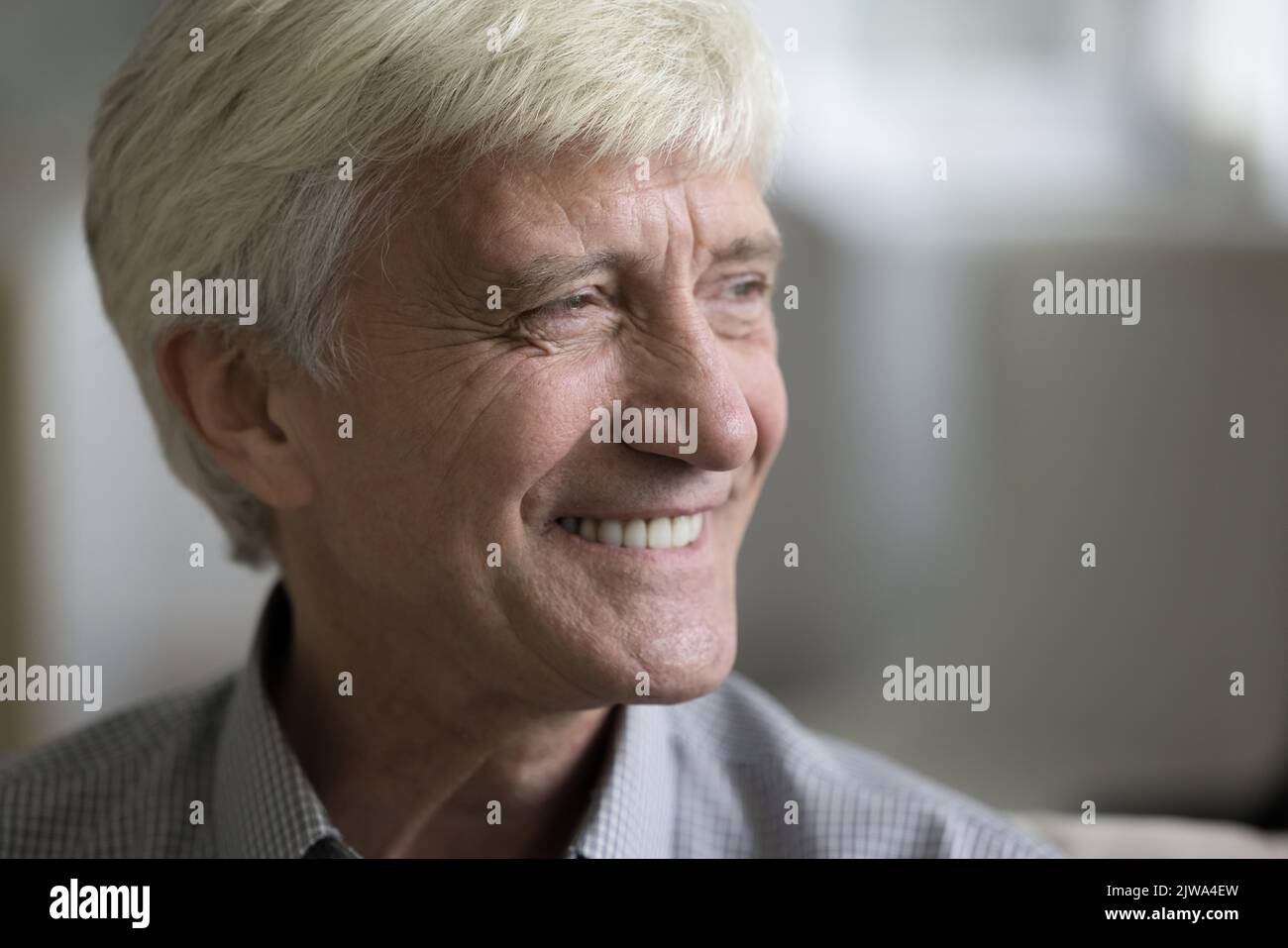Glücklicher, reifer, grauhaariger Mann, der mit toothy Lächeln wegschaut Stockfoto