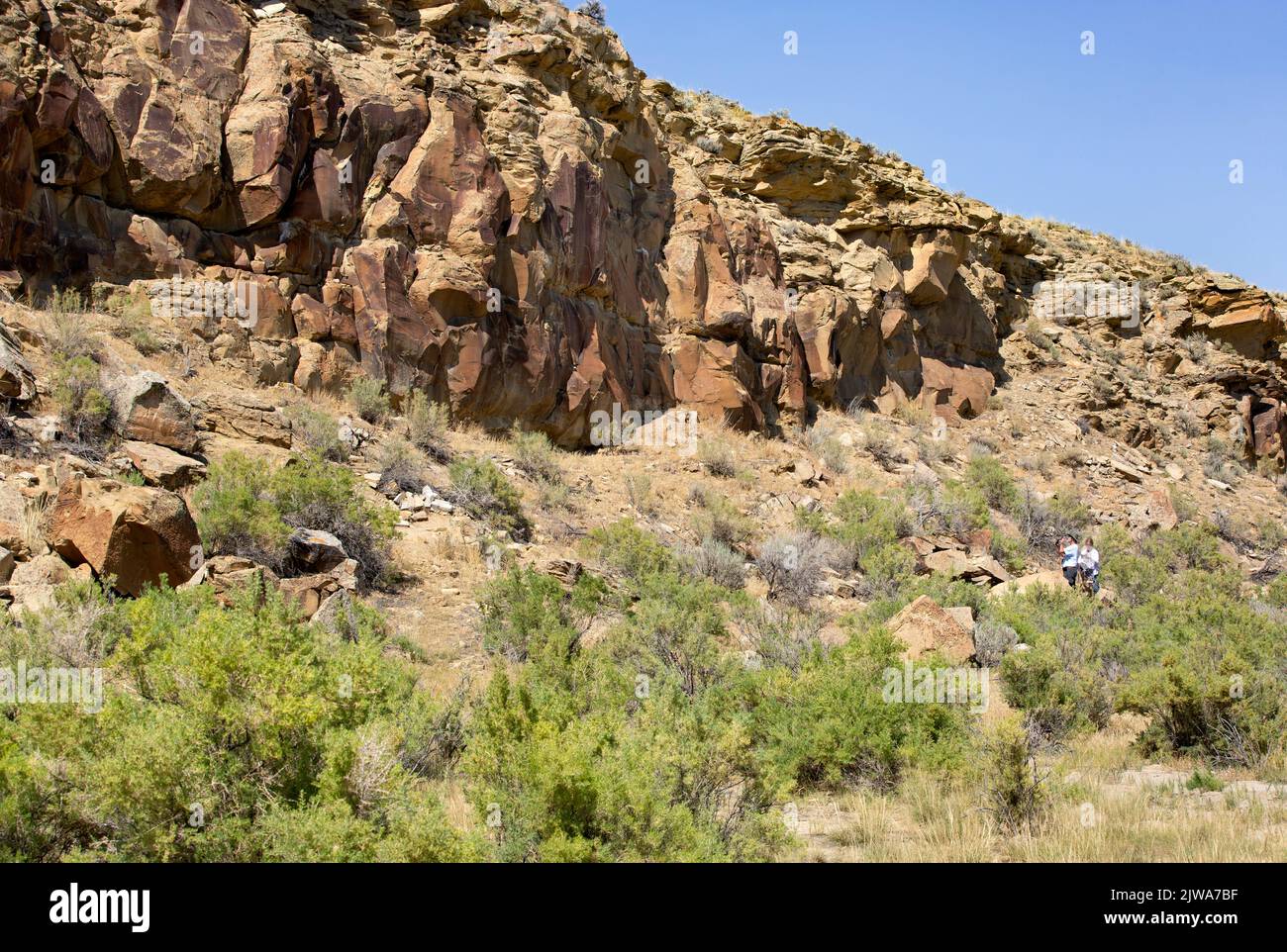 Touristen sehen die Felskunst der Ureinwohner Amerikas auf Sandsteinplatten in Legend Rock State Archaeological Site, Wyoming Stockfoto