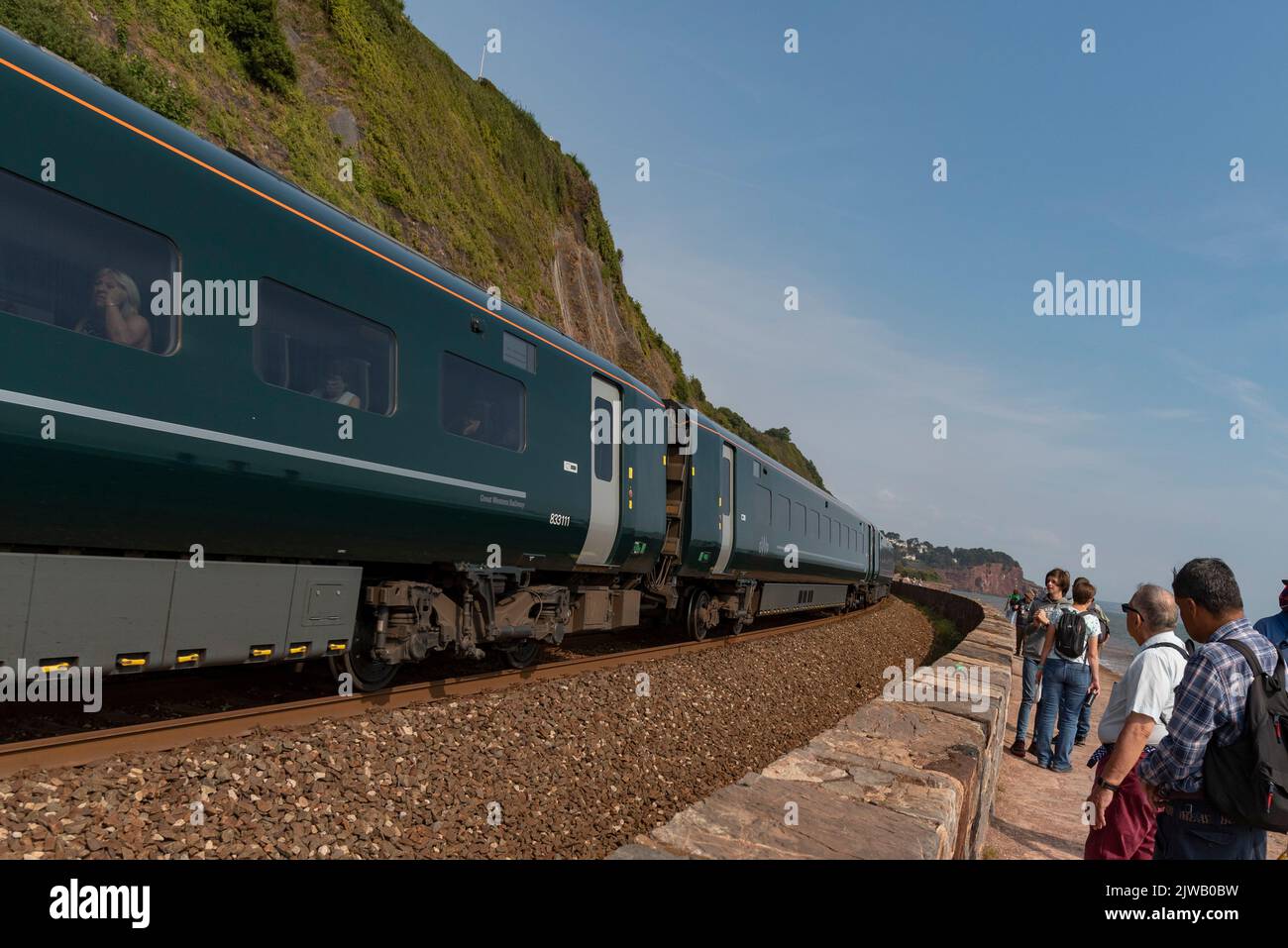 Teignmouth, Devon, England, Großbritannien. 2022. Urlauber halten an der Gleisseite an, um einen Personenzug in Richtung Teignmouth an der Südwestküste zu sehen. Stockfoto
