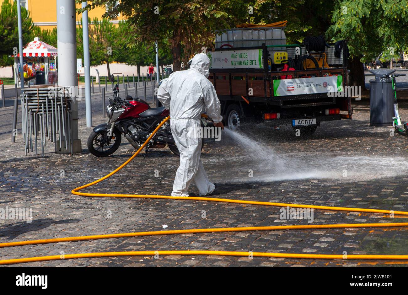 Einweg-Schutzanzug, weiß, mit voller PSA, Straßenreinigung mit Schlauchrohr in Lissabon, Portugal Stockfoto