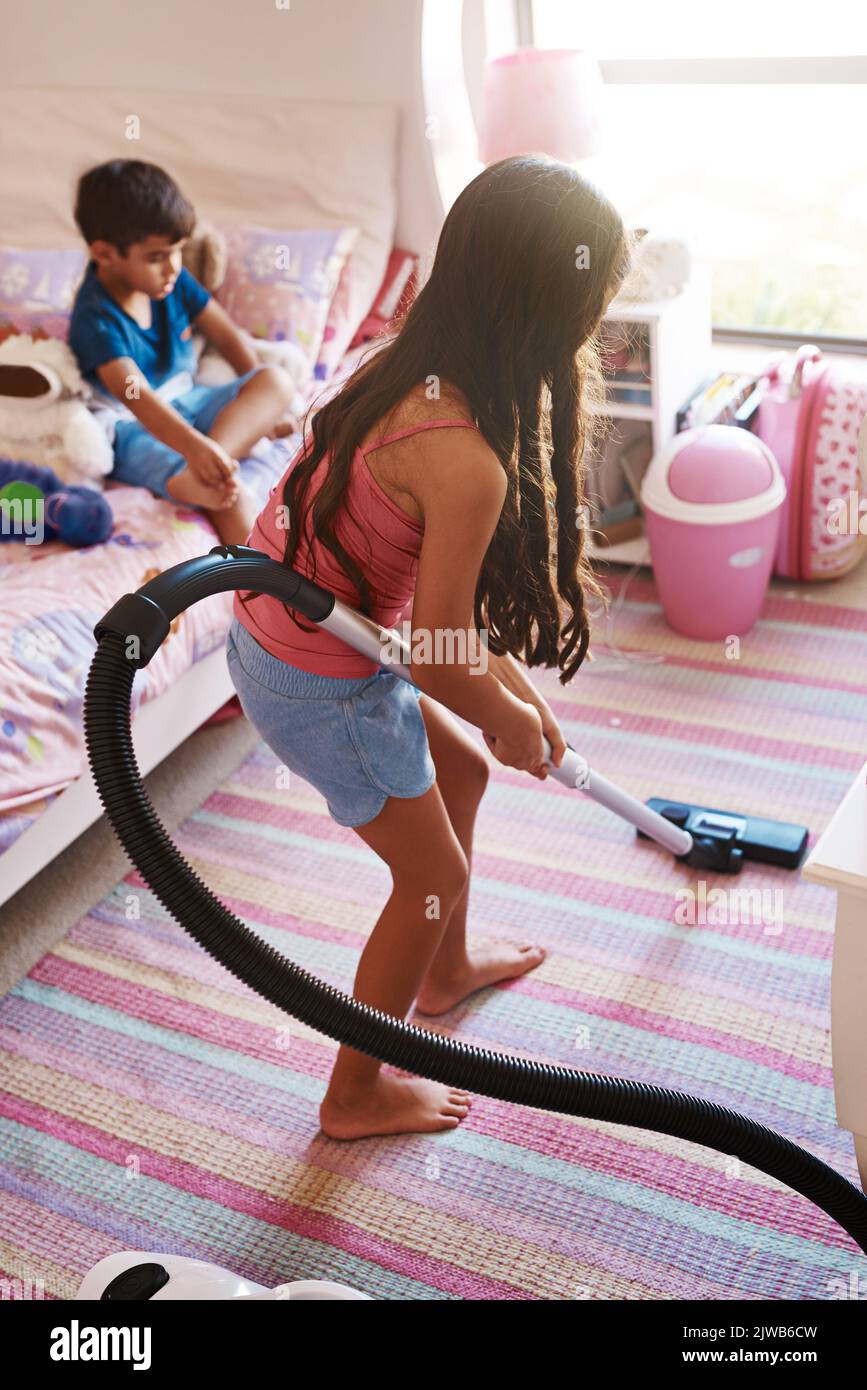 Ich habe diese Reinigung getan und entstaubt. Ein fokussiertes junges Mädchen, das einen Staubsauger benutzt, um sein Zimmer zu Hause zu reinigen. Stockfoto