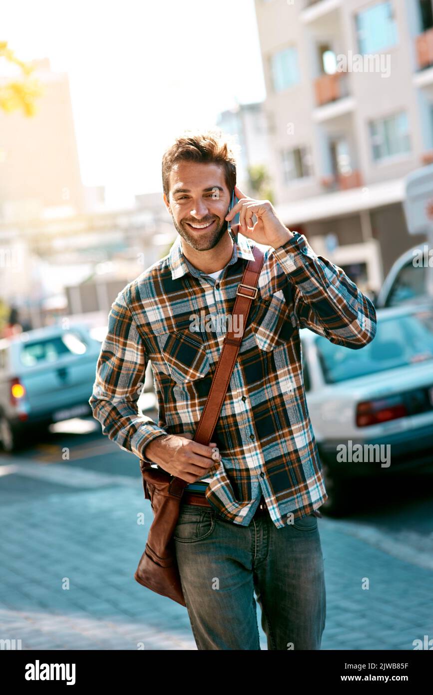 In Verbindung bleiben mit dem Stadtleben. Ein hübscher junger Mann, der sein Mobiltelefon benutzt, während er in der Stadt unterwegs ist. Stockfoto