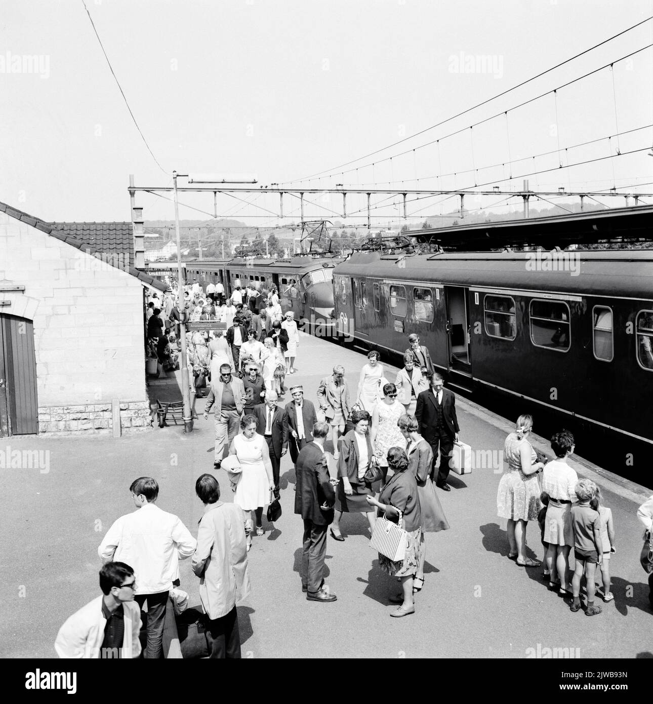 Bild von Menschenmengen mit Zugpassagieren beim ein- und Aussteigen in einem Zug und aus einem Elektrozug matt gesetzt. 1946 der N.S. Gekoppelt mit einem Zug Set matt. 1954 ('Valkenburg Expres') am N.S. Bahnhof Valkenburg. Stockfoto