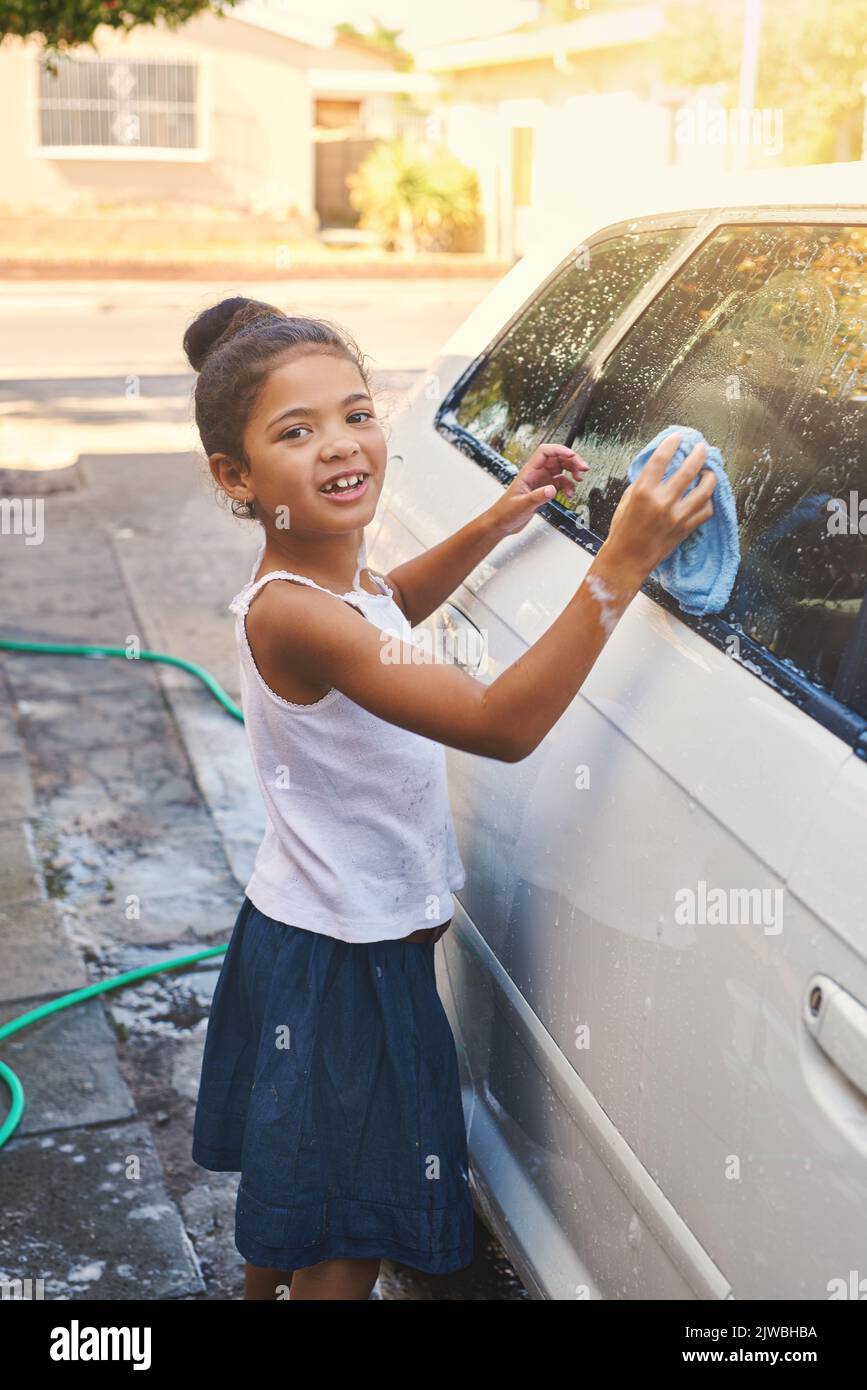 Schüttelt, bis es blitzsauber ist. Porträt eines jungen Mädchens, das damit beschäftigt ist, draußen ein Auto zu putzen. Stockfoto