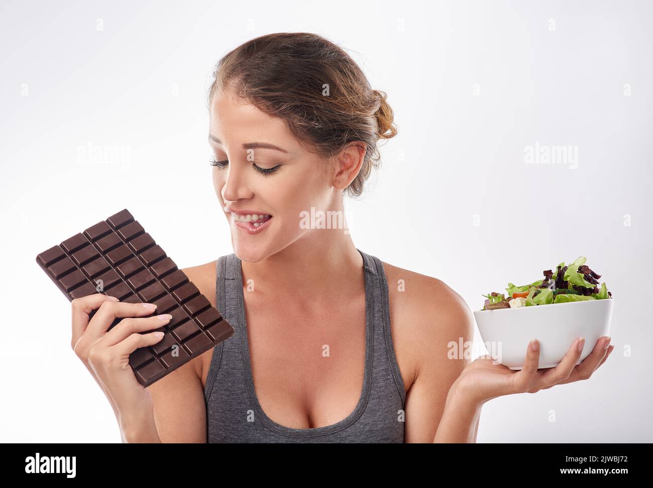 Shes ein Liebhaber von Schokolade. Studioaufnahme einer attraktiven jungen Frau, die von etwas Süßem verlockt wird. Stockfoto