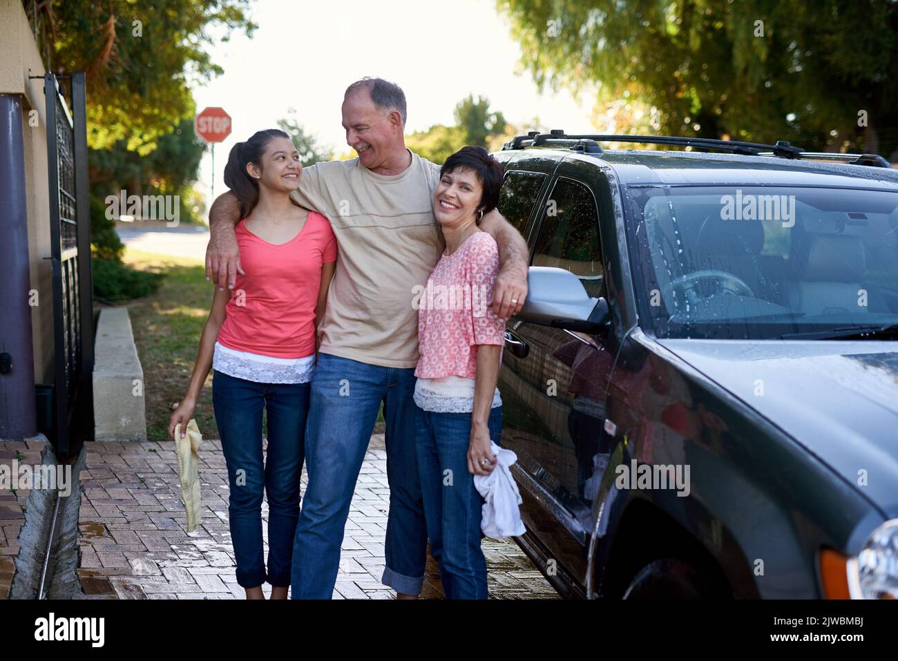 Sie arbeiten gerne als Team. Eine Familie, die draußen ein Auto gemeinsam wäscht. Stockfoto