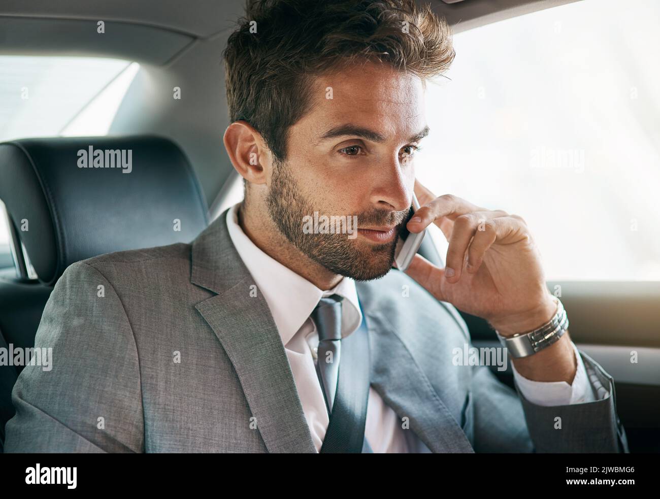 Erfolg ist alles über diesen Antrieb. Ein hübscher junger Geschäftsmann, der ein Handy auf dem Rücksitz eines Autos benutzt. Stockfoto