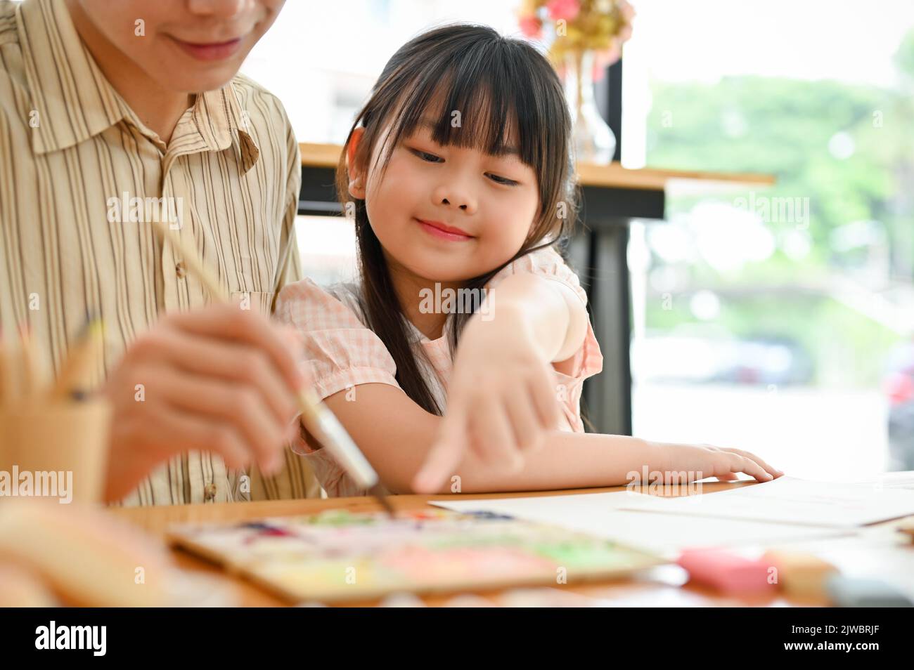 Glücklich und lächelnd junge asiatische Mädchen genießen Malerei Aquarell mit ihrem Vater auf dem Kind Kunst-Workshop. Close-up Bild Stockfoto