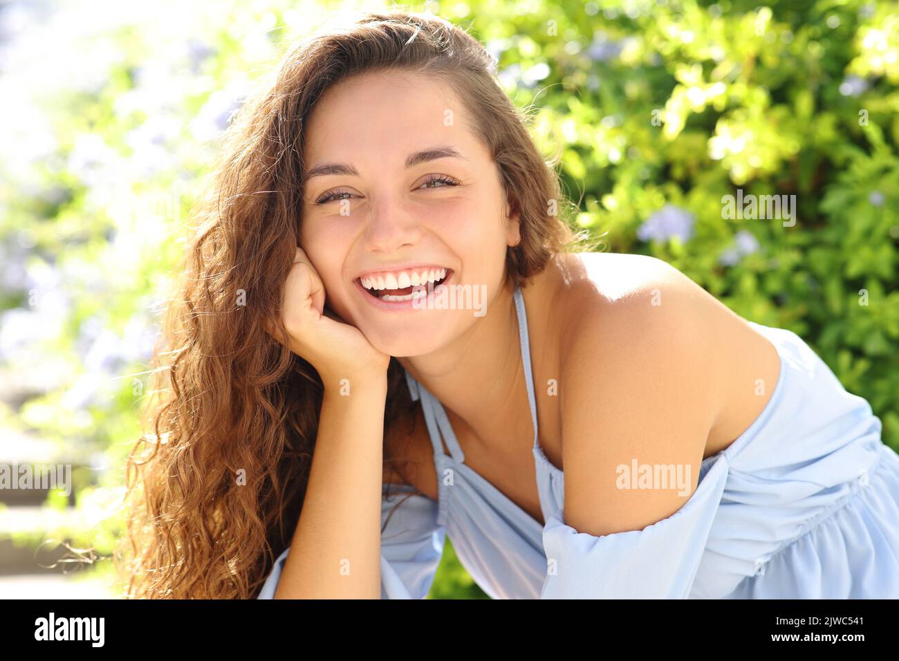 Porträt einer glücklichen Frau, die in einem Garten die Kamera anlächelt Stockfoto