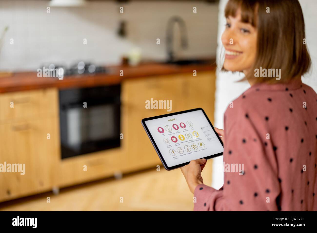 Frau steuert Heimgeräte mit einem digitalen Tablet zu Hause Stockfoto