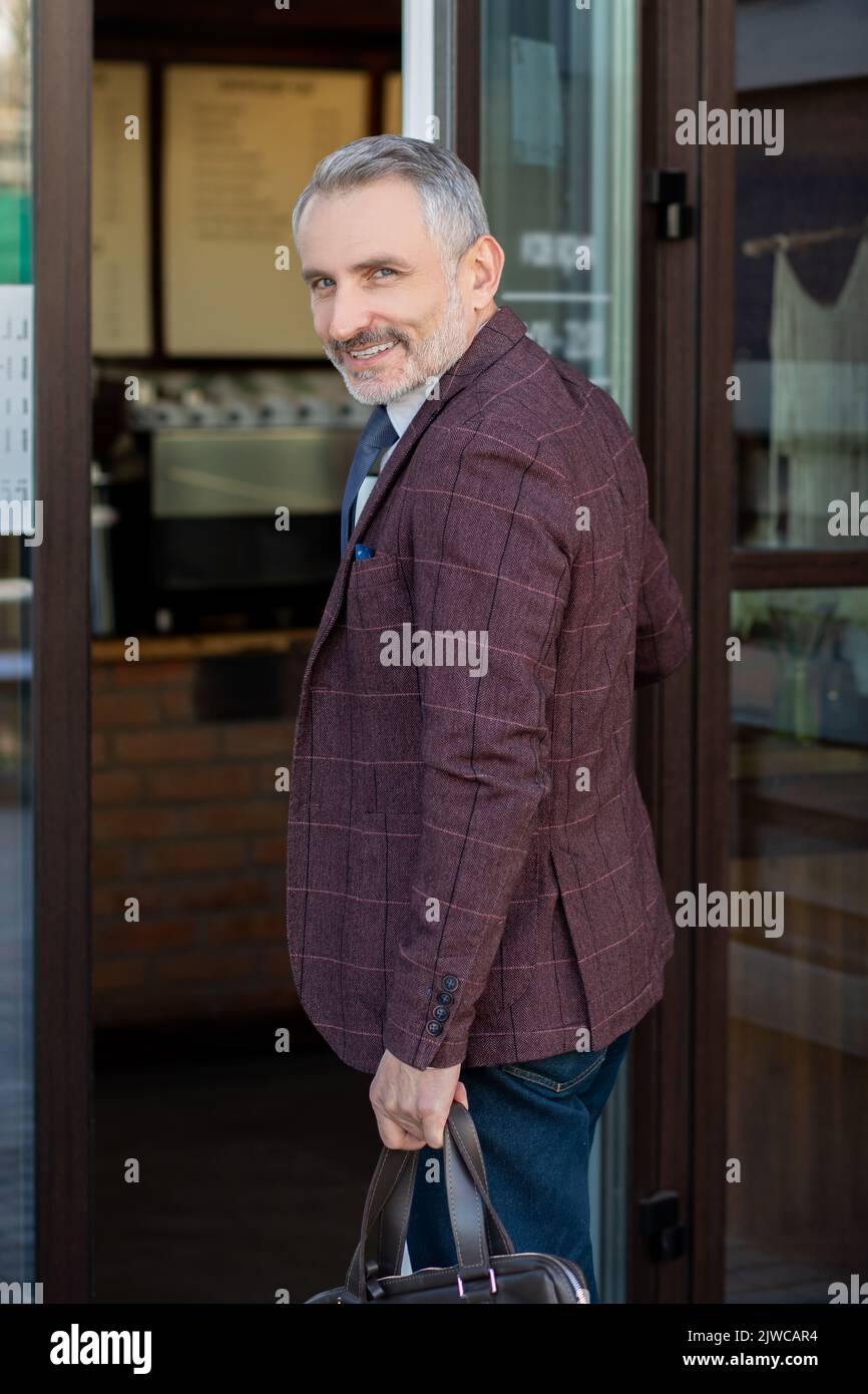 Fröhlicher, eleganter, reifer Mann, der das Café betrat Stockfoto