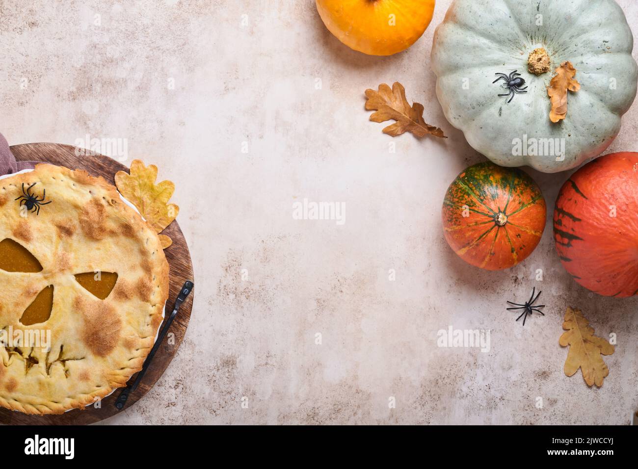 Halloween-Essen. Hausgemachter Kürbiskuchen oder Torte mit einem gruseligen Gesicht für Halloween auf einem Holztisch. Speicherplatz kopieren. Halloween-Food-Konzept. Stockfoto