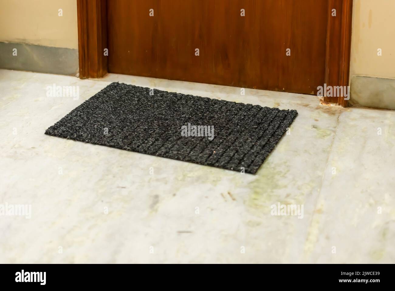 Eine schwarze rechteckige Bodenmatte neben einer Tür. Stockfoto