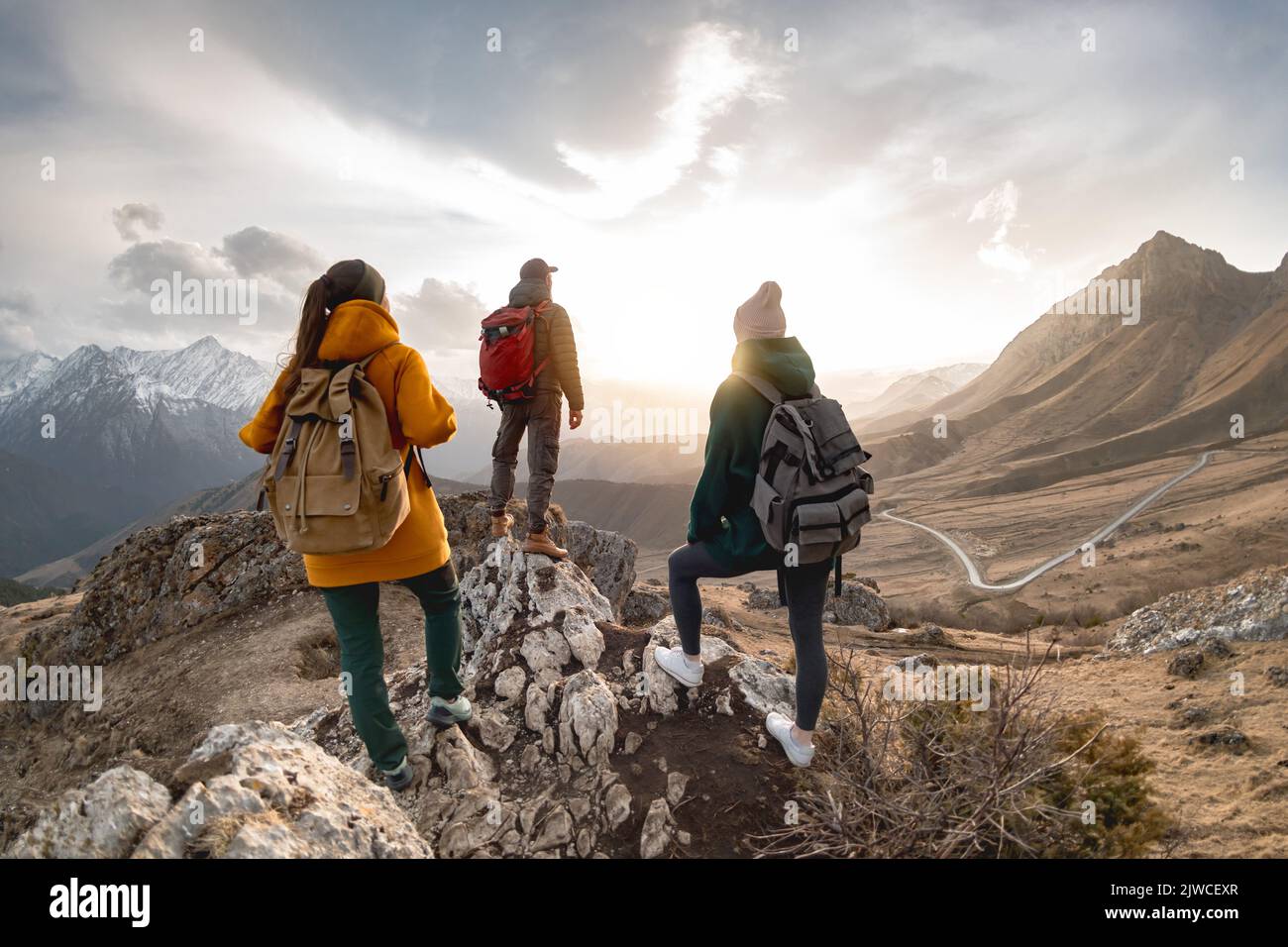Eine Gruppe von Wanderern oder Touristen mit Rucksäcken spaziert in den Bergen bei Sonnenuntergang Stockfoto
