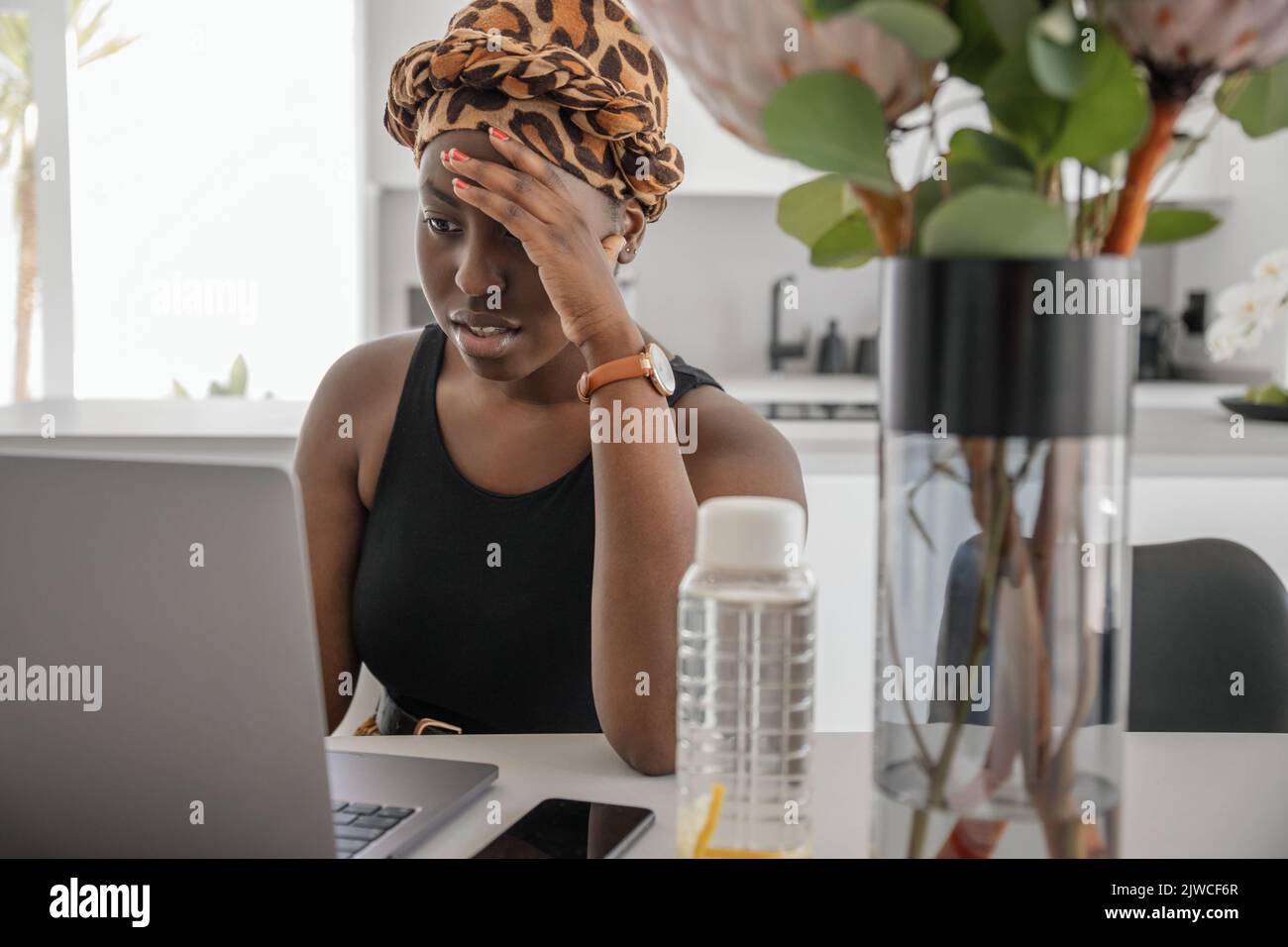 Junge schwarzafrikanische Frau müde, erschöpft von der harten Arbeit, die sie von zu Hause aus studiert. Gelangweilt und frustriert beim Blick auf ein Notebook. Kopf liegt auf der Hand. Stress Stockfoto
