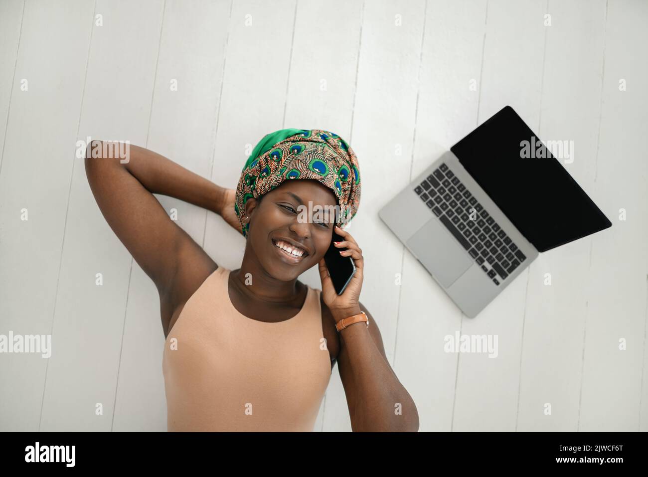 Draufsicht auf eine schöne junge afrikanische Frau mit einem traditionellen Kopftuch. . Am Telefon lächelnd Stockfoto