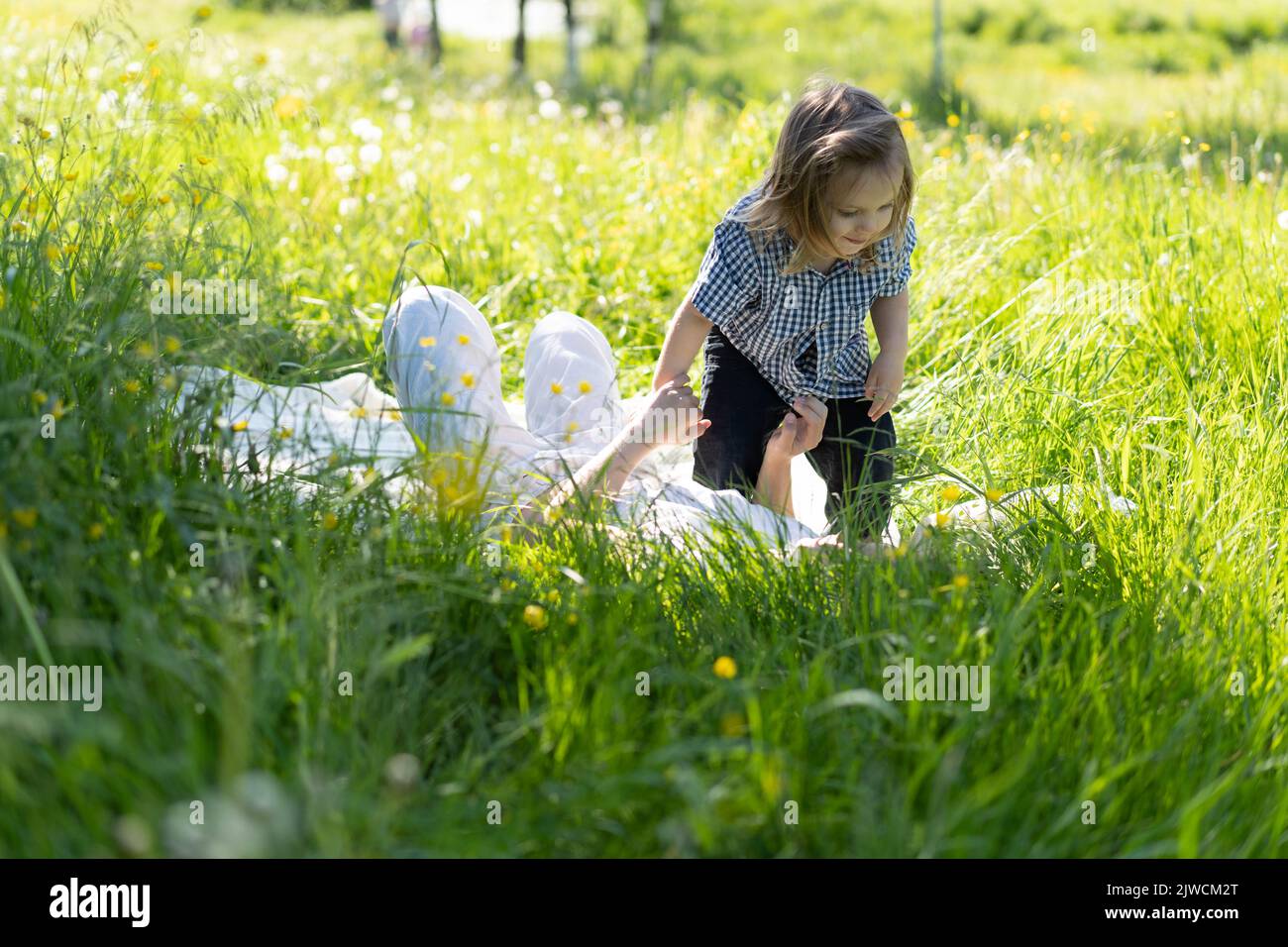 Bruder und Schwester laufen glücklich und lachen auf dem grünen Gras. Die Sonne scheint, die Kinder tanzen sorglos. Das Konzept eines glücklichen Familienlebens und der Bindung. Lifestyle. Stockfoto