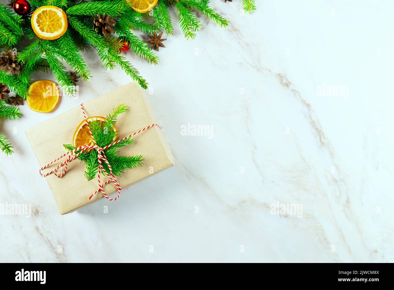 Zweige eines Weihnachtsbaums mit einer Null-Abfall-Geschenkbox, Kegeln, Weihnachtskugeln, Orangenscheiben und auf einem hellen Hintergrund.Draufsicht. Schöner weihnachtlicher Hintergrund Stockfoto