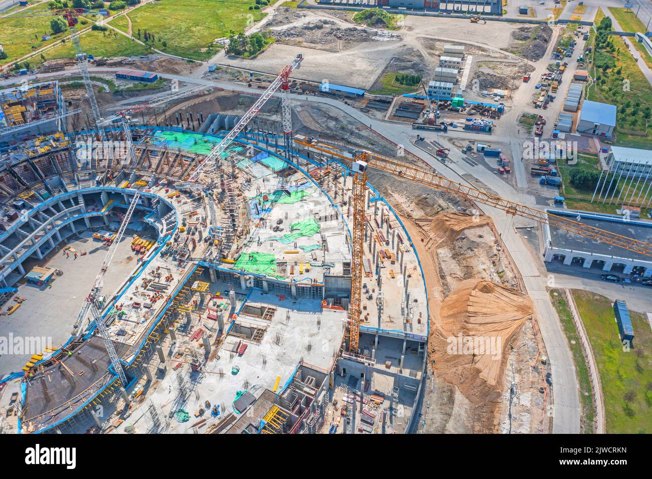 Bau auf einer riesigen Baustelle Kräne, Baustoffe. Das Konzept des Baus von großen Industrie- oder Sportanlagen Stockfoto
