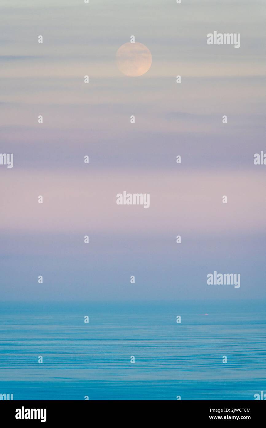 Von der Ostküste Siziliens aus ein verschwommener abstrakter Blick auf einen Vollmond, der an einem perfekten Sommerabend über dem Ionischen Meer aufgeht Stockfoto