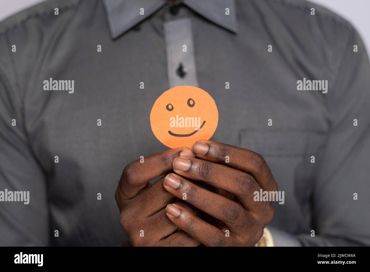 Schwarzer Mann hält Pappausschnitt lächelndes Emoji-Gesicht Stockfoto