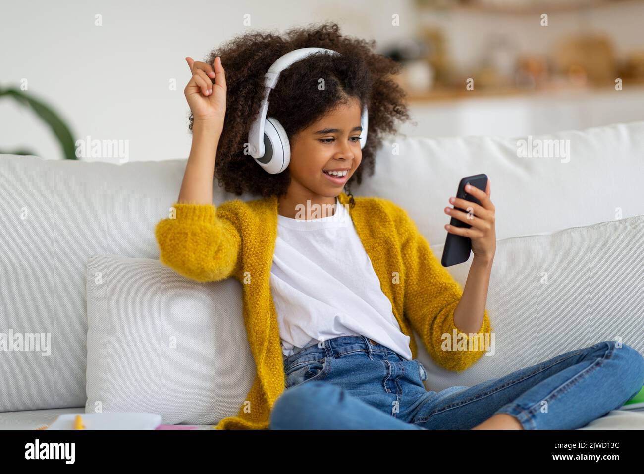Fröhliches afroamerikanisches Schulmädchen, das Musik hört Stockfoto