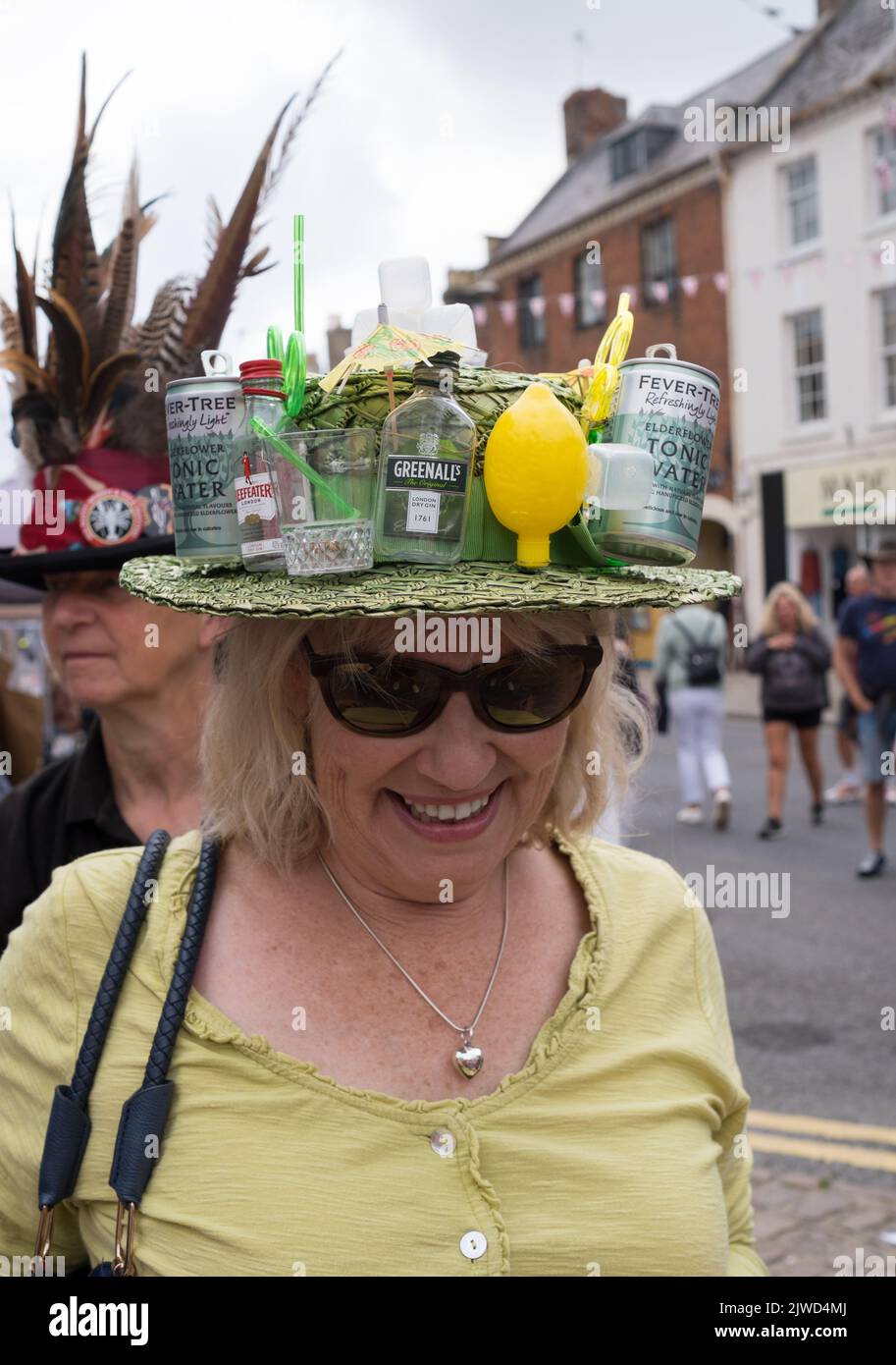 Lady in einem Gin und Tonic Hut genießt die Teilnahme am Bridport hat Festival Dorset 2022 Stockfoto