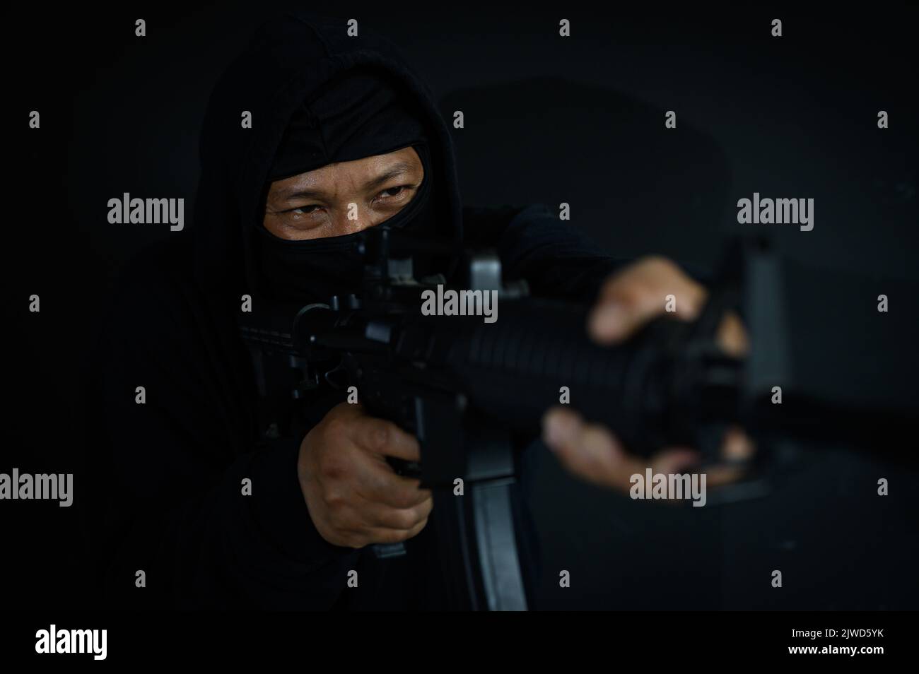 Bewaffneter Terrorist in schwarzer Balaclava Maske mit automatischer Waffe zielen Stockfoto