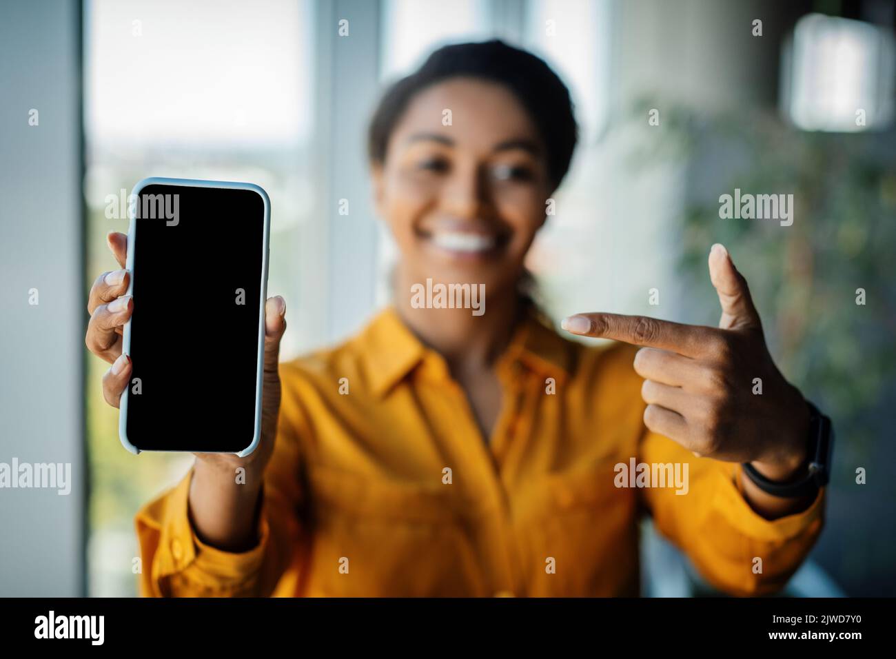 Tolles Angebot. Schwarze Geschäftsfrau, die mit dem Finger auf das Mobiltelefon mit leerem Bildschirm zeigt und die App oder Website fördert Stockfoto