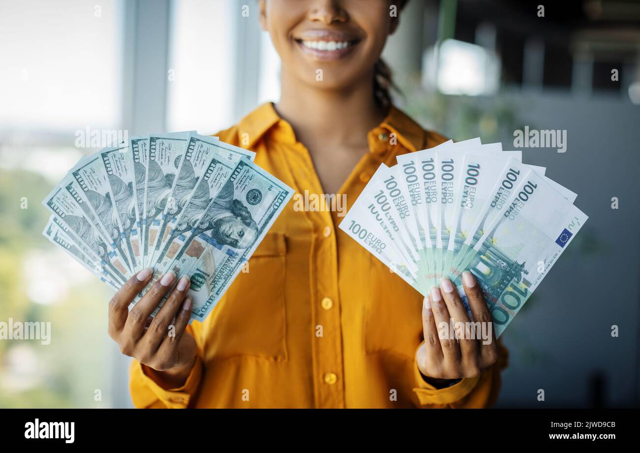 Erfolgskonzept erreichen. Wohlhabende schwarze Geschäftsbesitzerin, die Geld-Dollar-Bargeld zeigt und im Büro steht Stockfoto