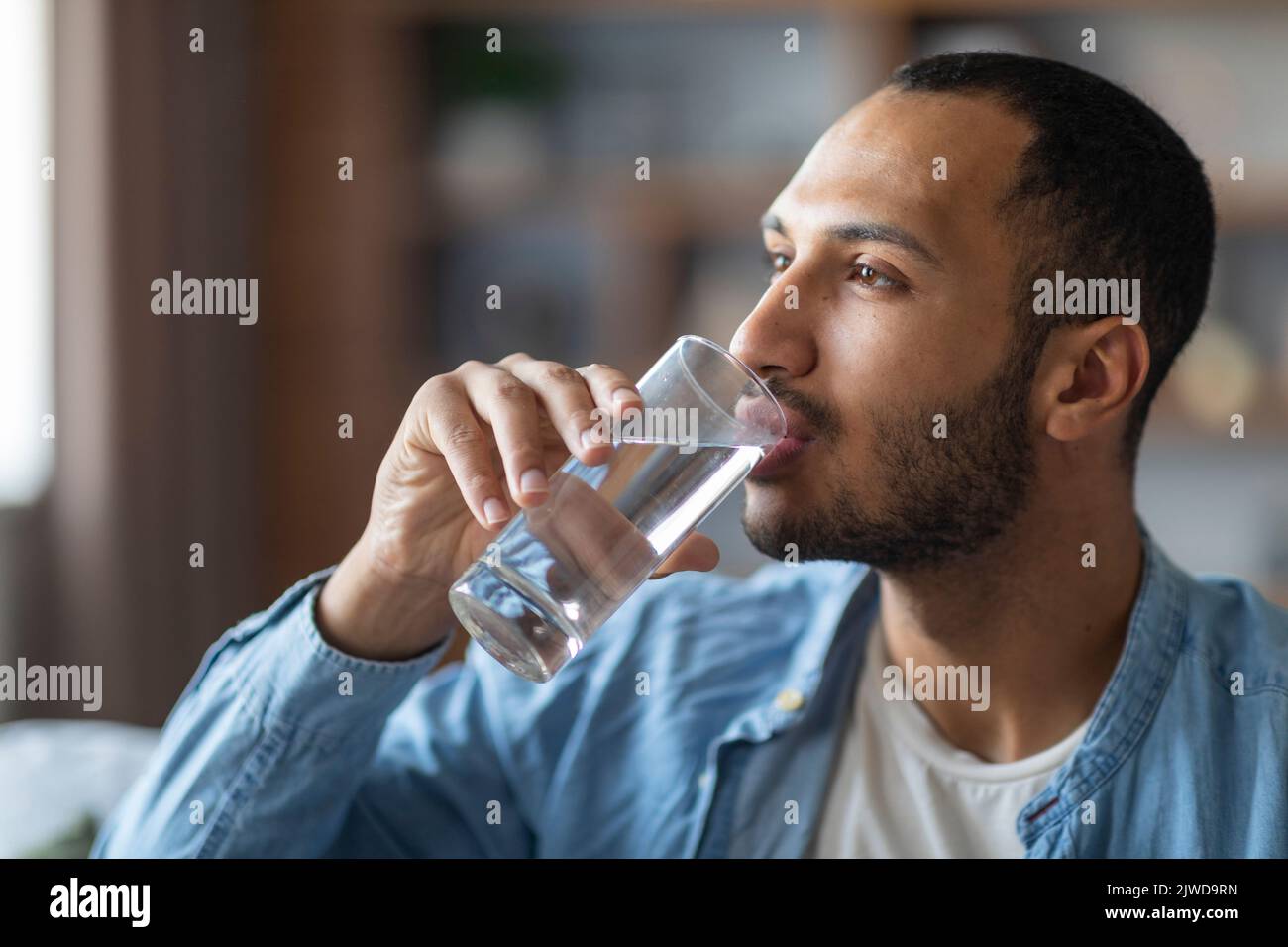 Porträt Eines Hübschen Jungen Schwarzen Mannes, Der Wasser Aus Glas Trinkt Stockfoto