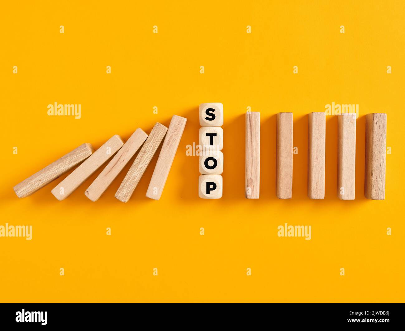 Holzwürfel mit dem Wort stop stoppt die fallenden Holzblöcke. Den Dominorisikoeffekt oder die Risikoprävention im Geschäftskonzept zu stoppen. Stockfoto