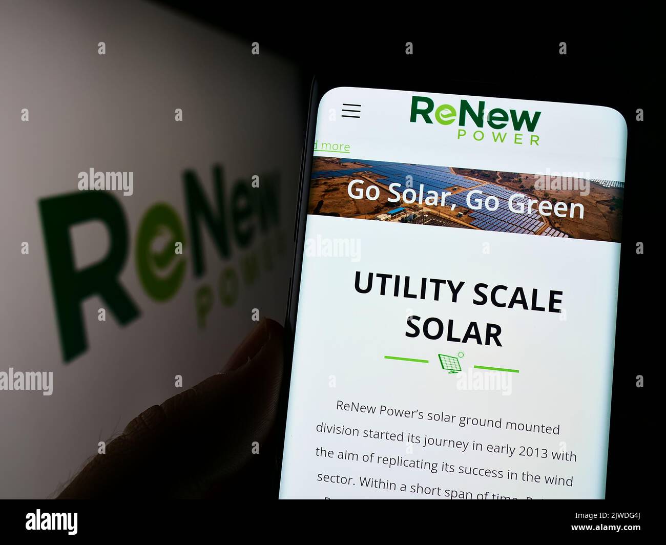 Person, die Mobiltelefon mit der Website des indischen Unternehmens Renew Energy Global plc auf dem Bildschirm vor dem Logo hält. Konzentrieren Sie sich auf die Mitte des Telefondisplays. Stockfoto