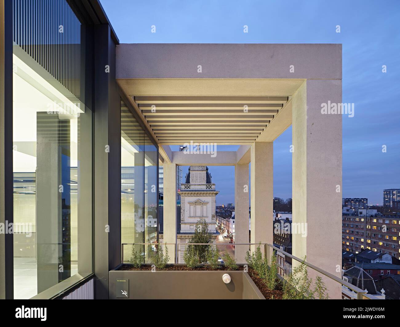 Blick auf die Außenfassade der oberen Etage in der Abenddämmerung. 50 Eastbourne Terrace, London, Großbritannien. Architekt: Sheppard Robson, 2021. Stockfoto