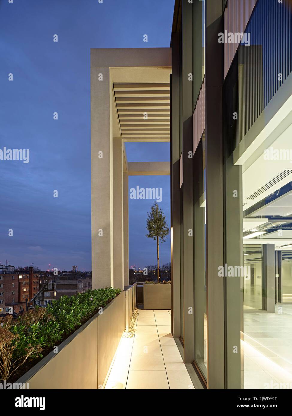 Blick auf die Außenfassade der oberen Etage in der Abenddämmerung. 50 Eastbourne Terrace, London, Großbritannien. Architekt: Sheppard Robson, 2021. Stockfoto