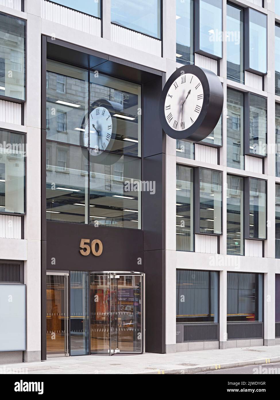 Übergroße Fassadenuhr mit Malzeit für Figuren am Haupteingang. 50 Eastbourne Terrace, London, Großbritannien. Architekt: Sheppard Robson, 2021. Stockfoto