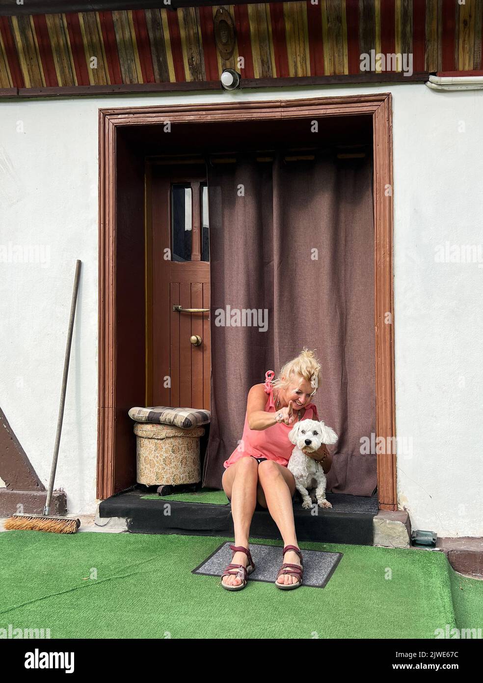 Frau, die mit ihrem Pudel vor der Haustür sitzt, Polen Stockfoto