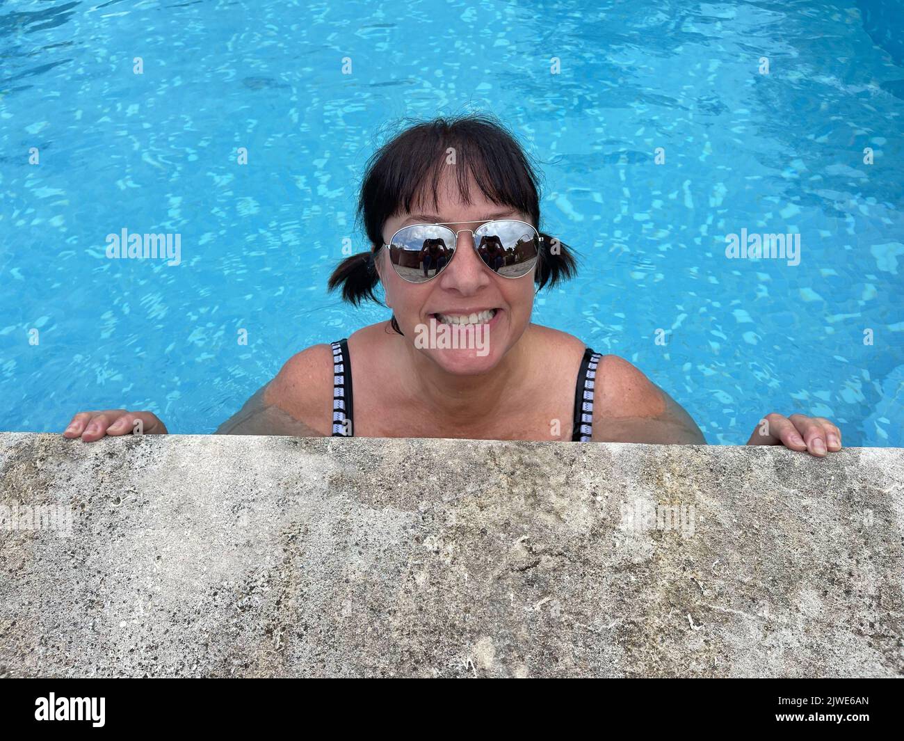 Porträt einer lächelnden Frau, die den Rand eines Schwimmbades hält, Frankreich Stockfoto