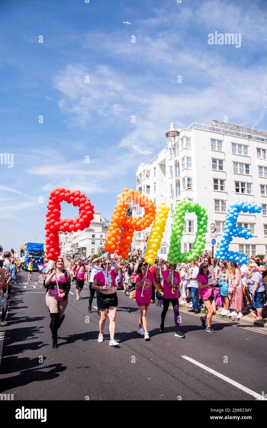 Menschen, die Luftballons tragen und Pride bei der Brighton Pride Parade 2022 schreiben Stockfoto