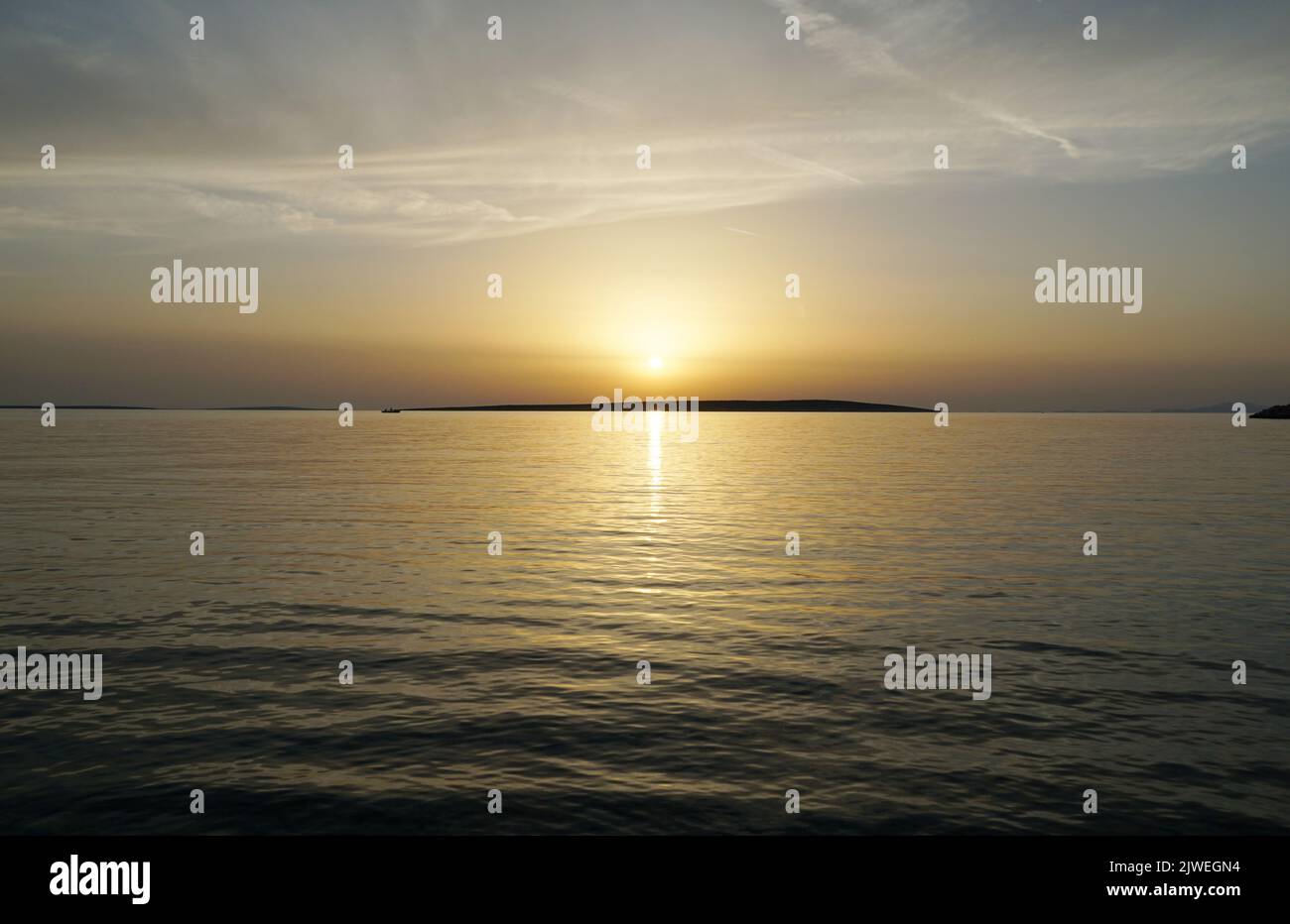 Ruhige und entspannende Atmosphäre während des Sonnenuntergangs über der glasigen Meeresoberfläche zur goldenen Stunde Stockfoto