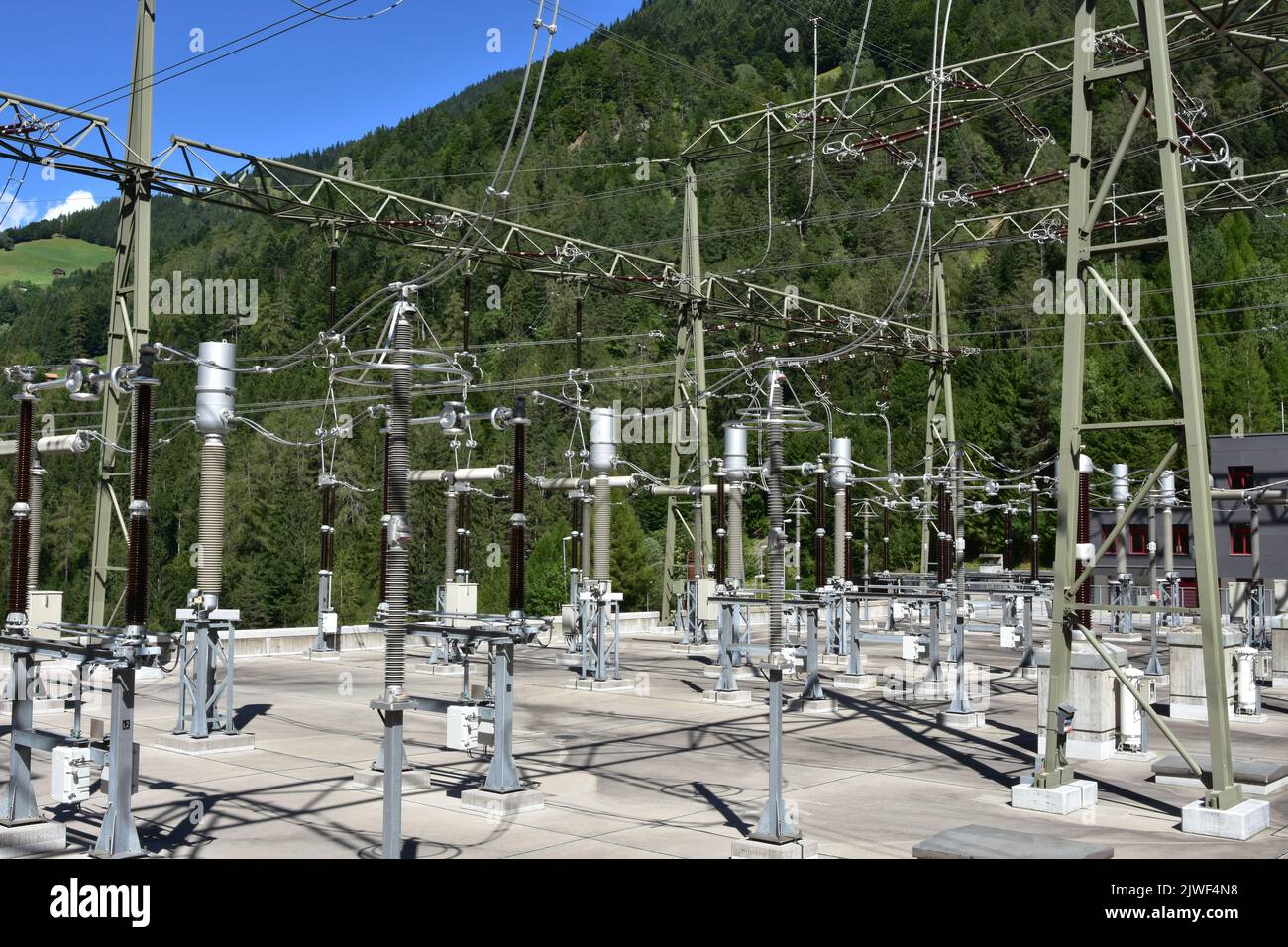 Elektromasten mit Überkopfkabeln, Ausleitungssicherungen, Überspannungsableiter und anderen Komponenten als Teil des Wasserkraftwerks- Stockfoto