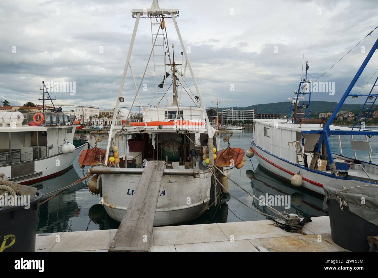 Weißes Fischerboot, das im Hafen in der Stadt Koper in der Nähe des Stadtzentrums festgemacht ist. Stockfoto