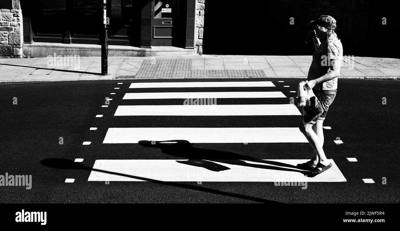 Eine Person, die auf einer brandneuen Zebrakreuzung die Straße überquert Stockfoto